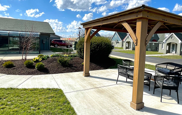 Outdoor courtyard with gazebo covering and sitting area at senior living community.