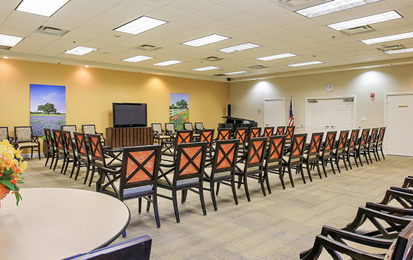 Activity room at a senior living community with ample seating and television.