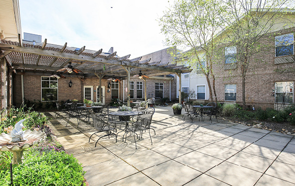 Outdoor courtyard with pergola, seating and patio at senior living community.
