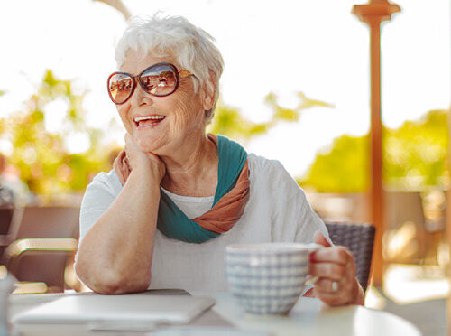 Smiling senior woman holding a mug at the table of her retirement home
