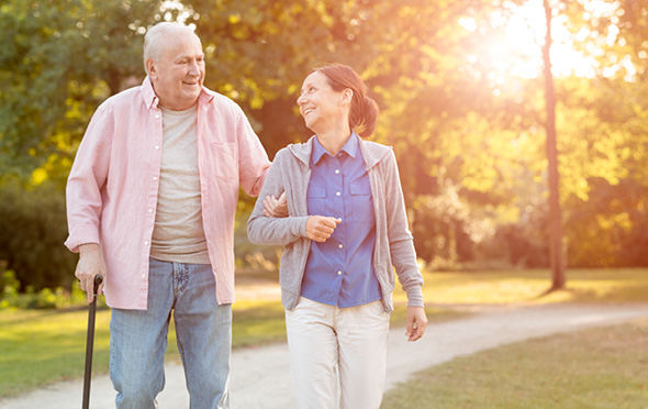 Senior man and his caregiver walking outside at his nursing home