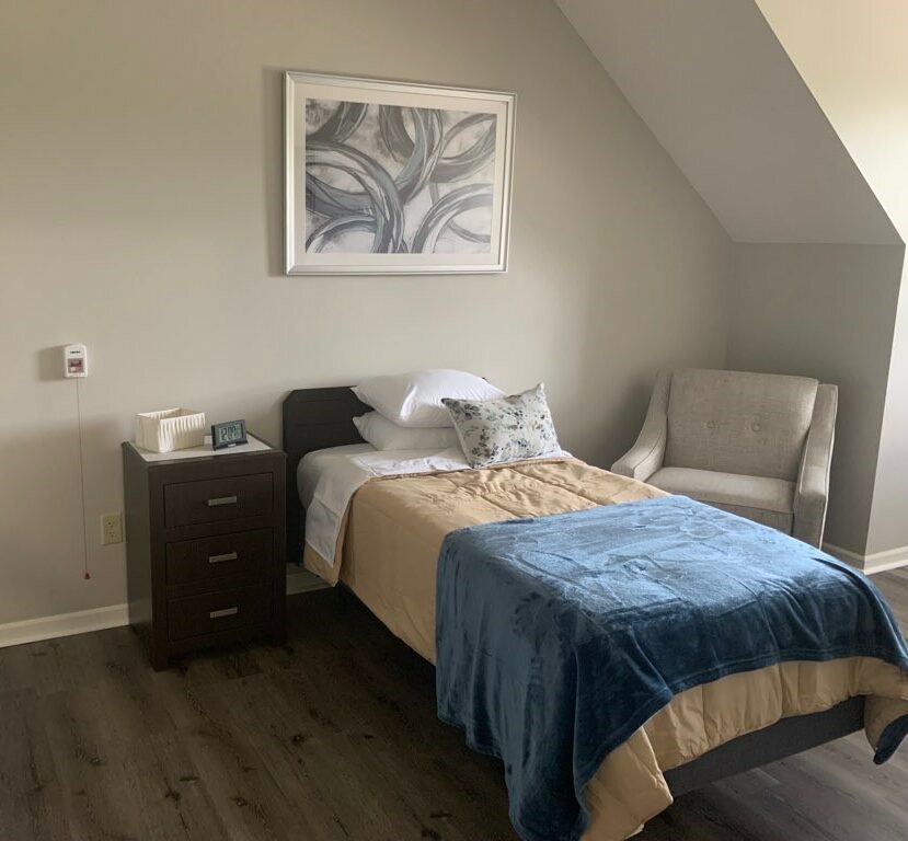 senior apartment bedroom with twin bed, side table and chair near a window