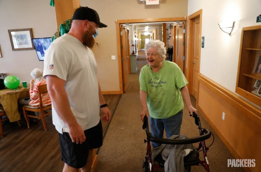 senior woman smiles while talking to a middle-aged man in a senior living community