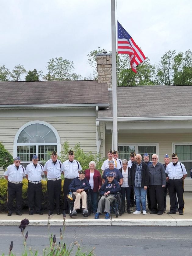 group of veterans gather around a flag pole outside a senior living community