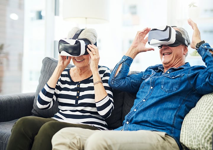senior couple use virtual reality headsets on the sofa together