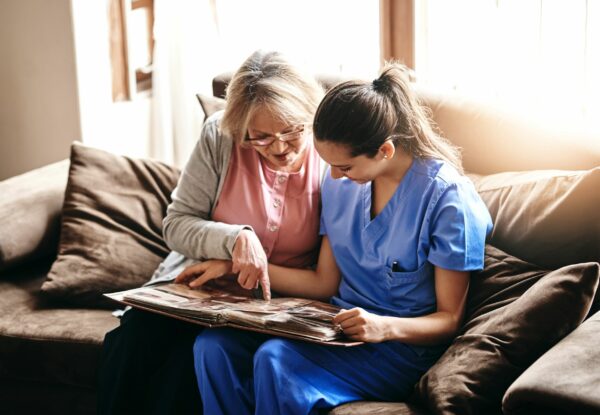 woman nurse and a senior woman looking at a photo album together