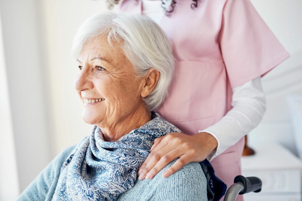 senior woman looking thoughtful while sitting with a nurse in her room