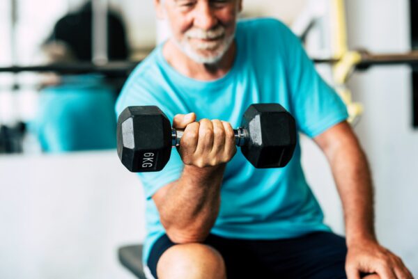 mature senior at the gym working his body with dumbbell