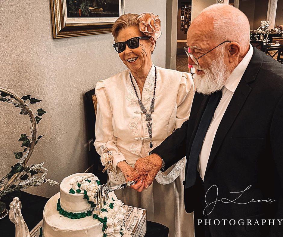 senior couple cut their wedding cake together while smiling