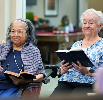 Educational and spiritual programs. Two senior women smile while participating in a bible study group