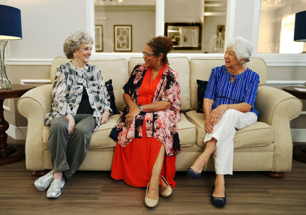 A group of senior ladies enjoying a chat on a couch in the common area of a Sonida Senior Living independent living community.