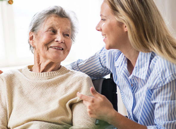 adult woman smiles and has her arm around an elderly woman