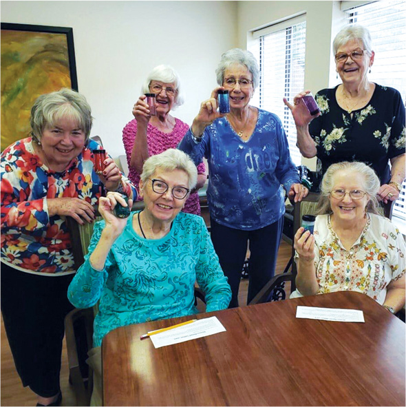 A group of friends smiling and showing their completed crafts after an activity in a Sonida Senior Living community.