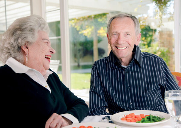 Smiling residents sharing a meal in a Sonida Senior Living assisted and independent living community.