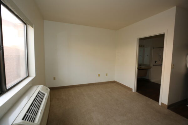 studio apartment living space with a window and a private bathroom