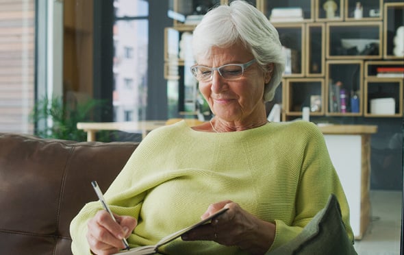 Senior woman writes in a journal about her New Year's resolutions