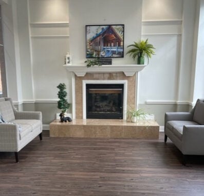 two couches near a fireplace inside the lobby of a senior living community