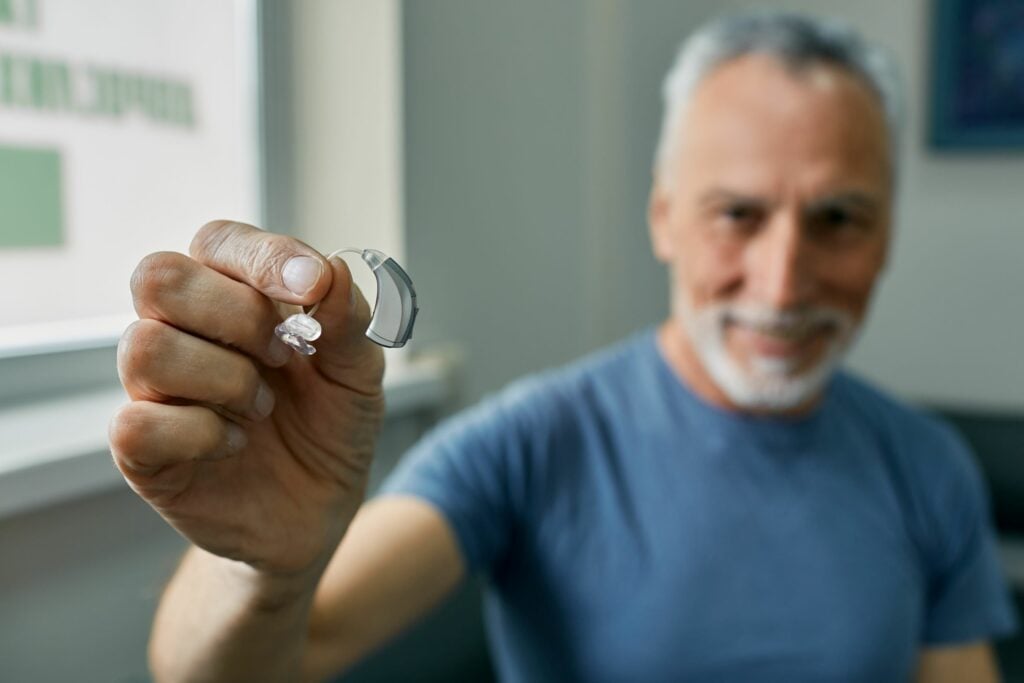 Senior man holds a BTE hearing aid