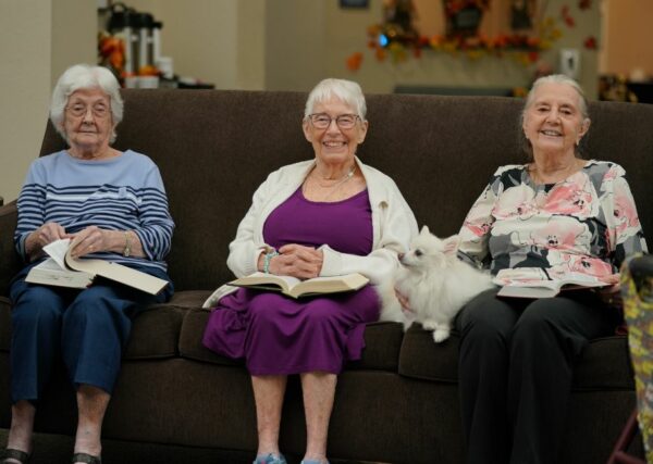 three senior women sit together on a couch during a bible study session