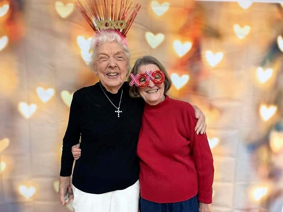 two senior women pose together during a Valentines Day party