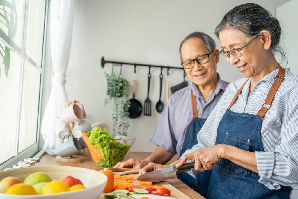 Asian senior elderly couple wear aprons and cook in the kitchen