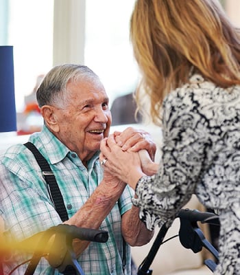 senior man smiles while holding the hands of the senior living director