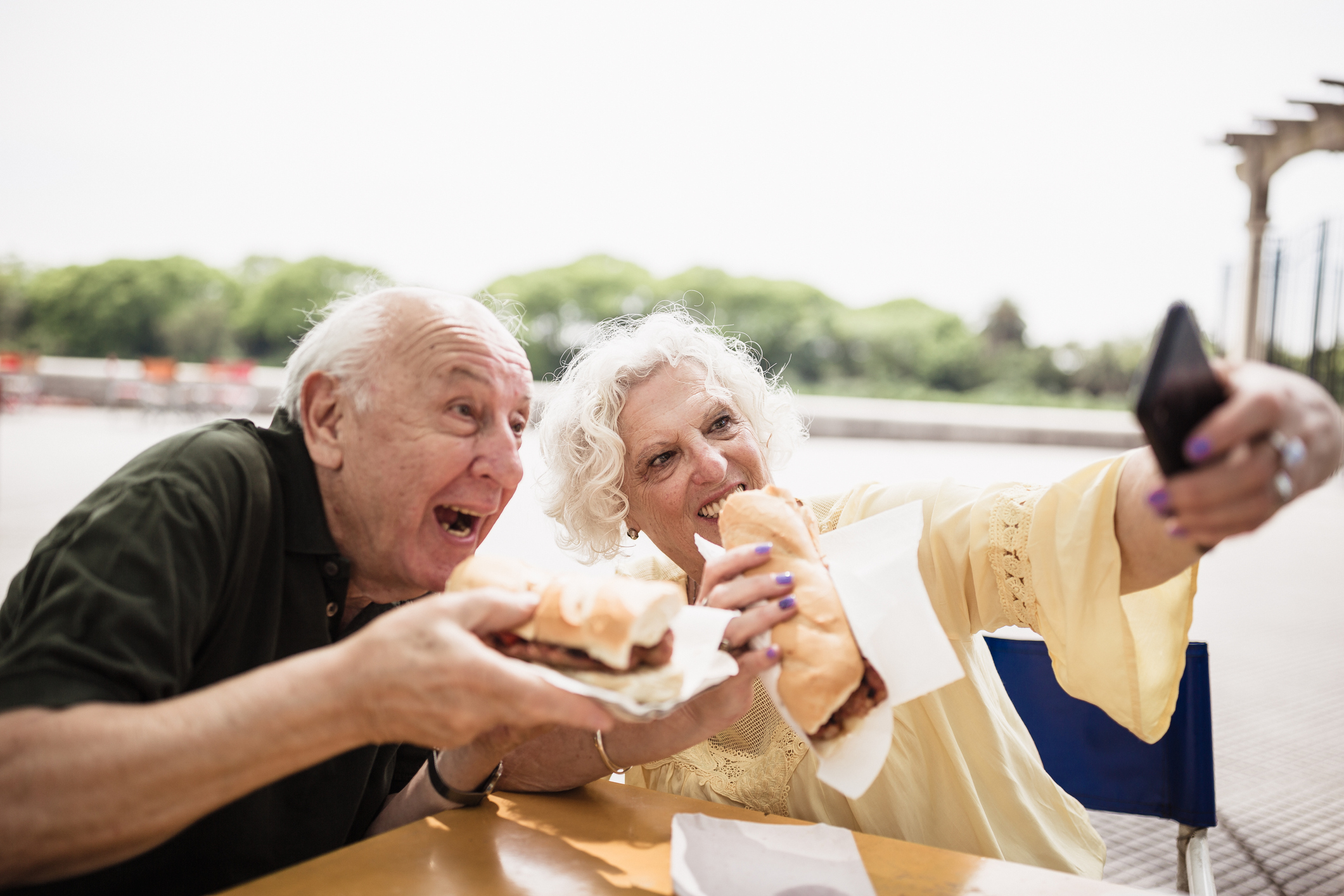 Senior couple eating food, taking selfies