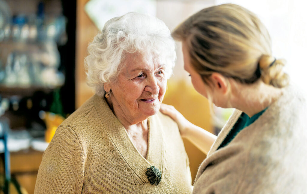 A female visitor talks to a senior woman with her hand on her shoulder