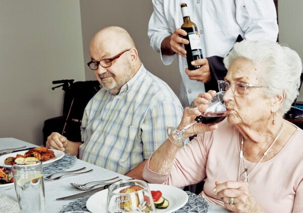 Senior woman tries a sip of wine at a dinner table with a senior man