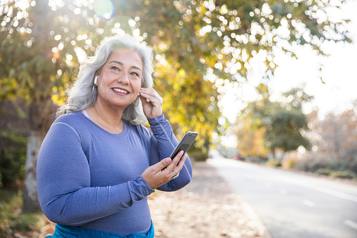 Senior woman on phone going outside for exercise.