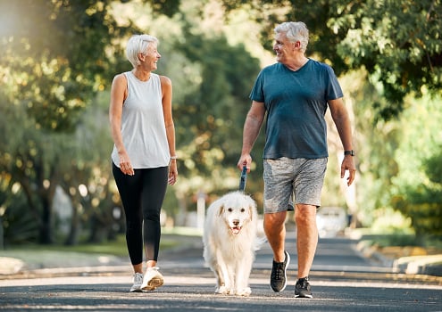 Senior woman and senior man with a dog going outside for exercise.