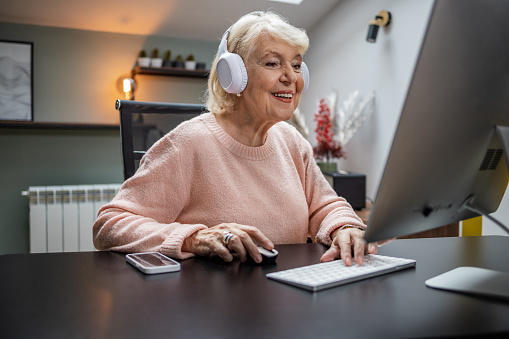 An older woman uses a computer at her senior living apartment