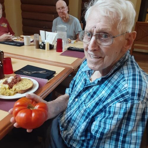 an old man holding a tomato