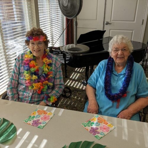 Two women working on crafts during a Hawaii themed event