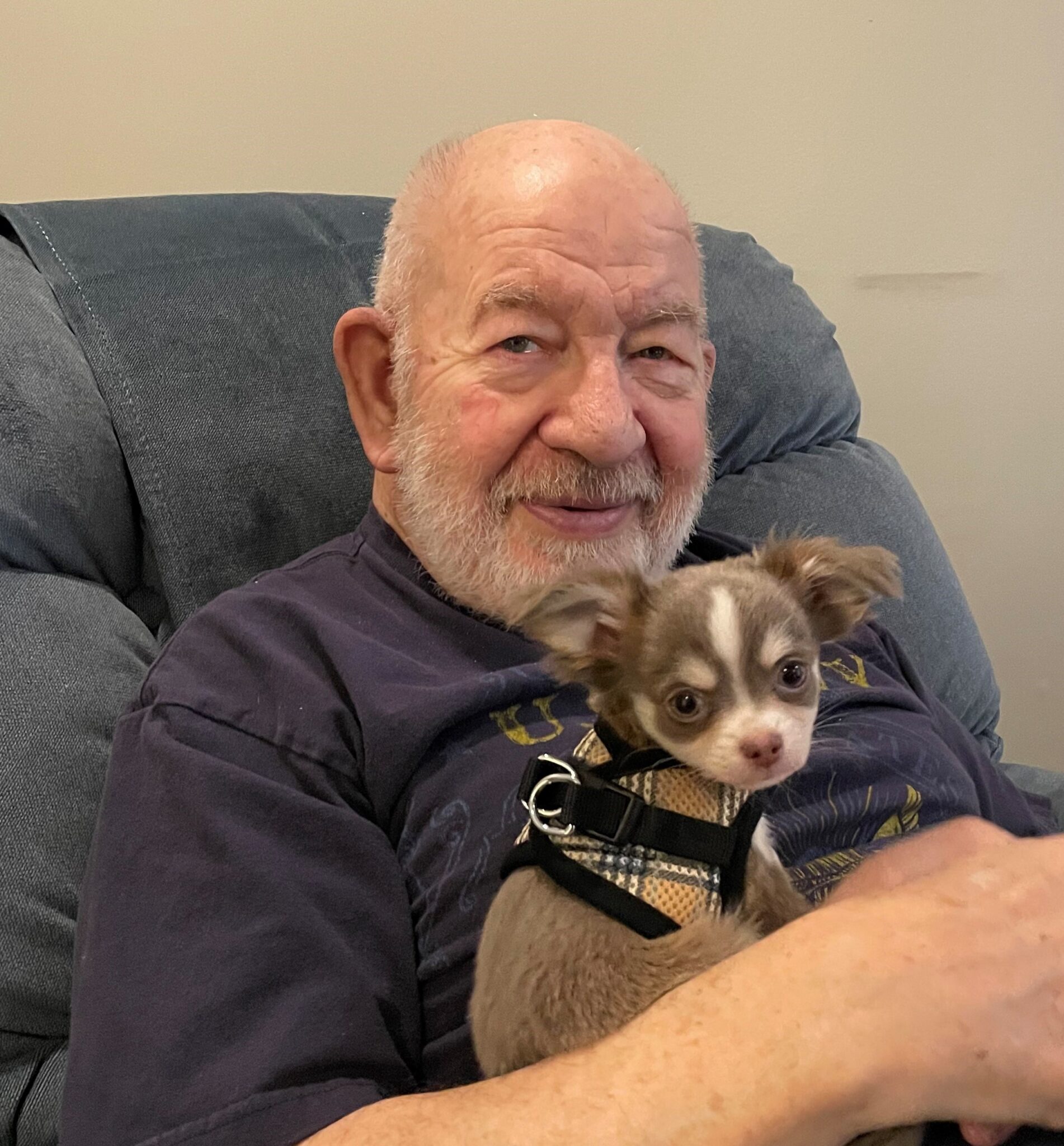 Male resident holds a small puppy during pet therapy