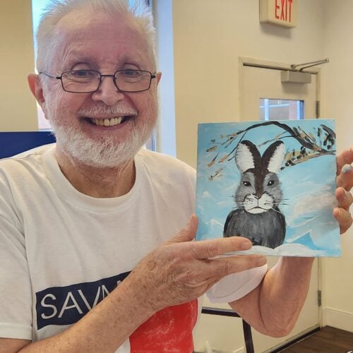 Senior man holding up his painting of a bunny