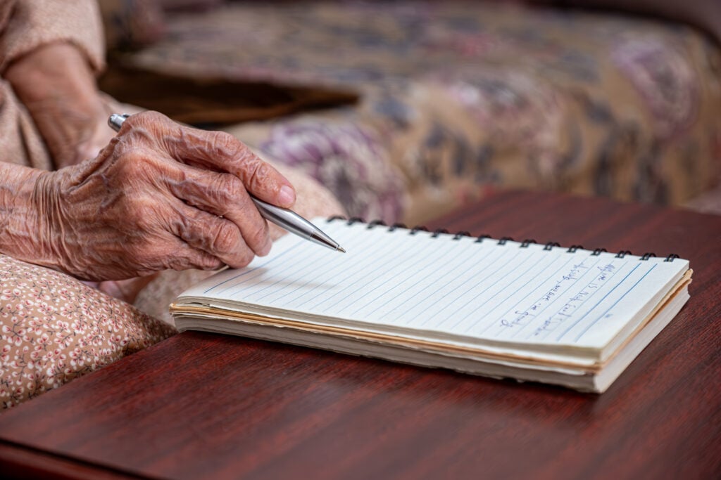 hands for elderly person writing notes on their note book