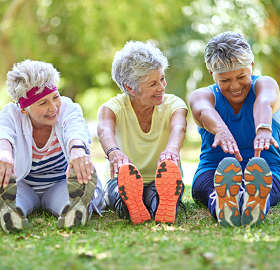 Three women stretching after a fitness class outside at a Sonida senior living community
