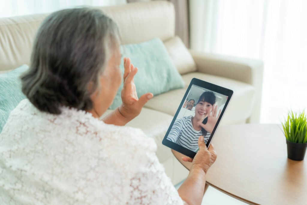 Asian elderly woman virtual happy hour meeting and talking online together with her daughter in video conference with tablet for a online meeting in video call for social distancing.