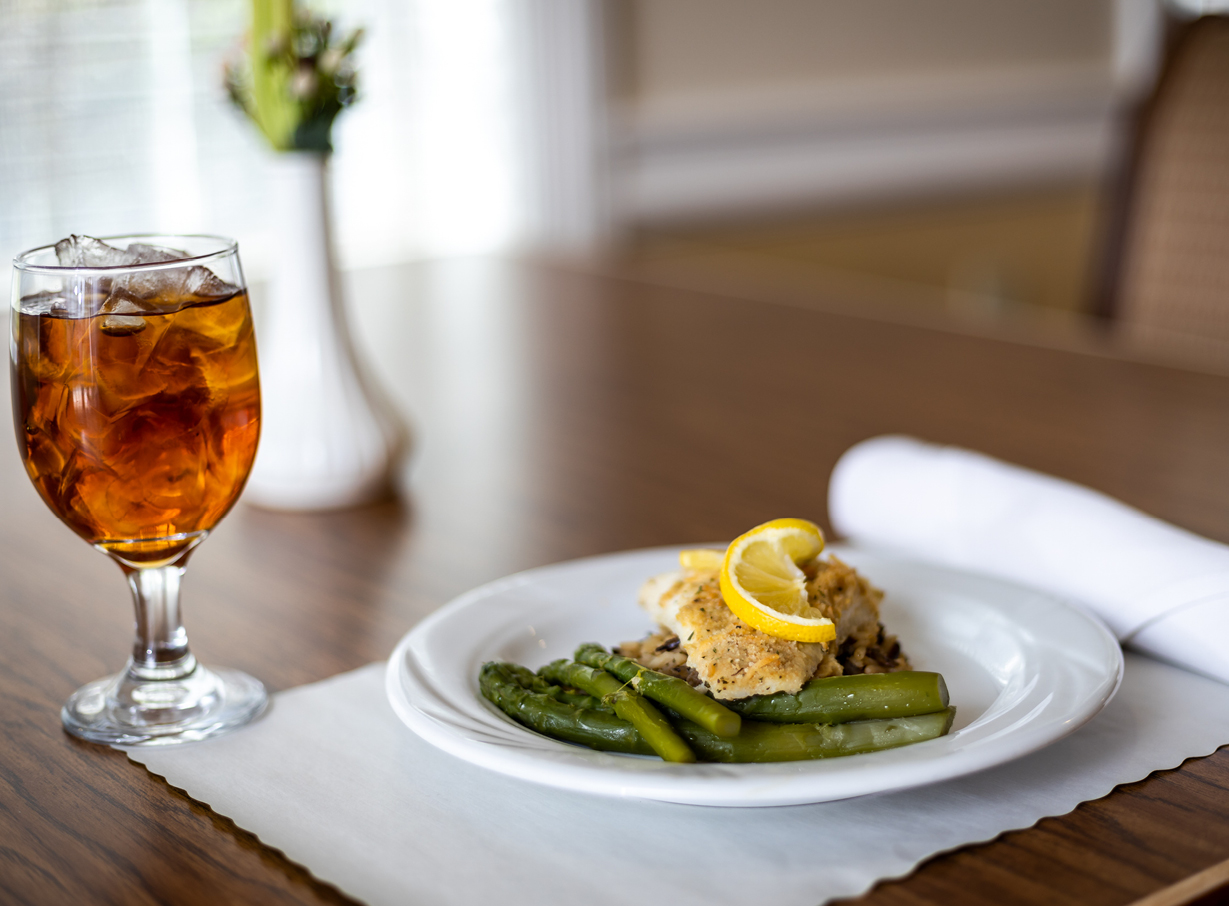 Example of food served at The Waterford at Shavano Park, including a piece of fish, asparagus, and iced tea
