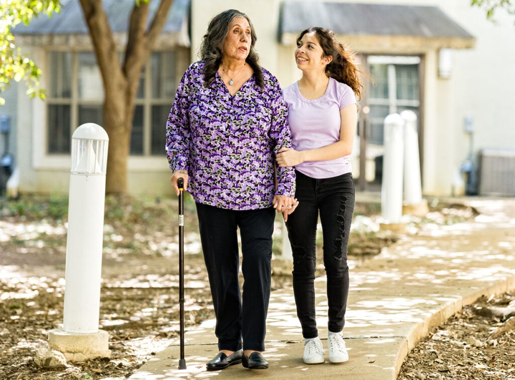 A senior woman smiling and walking with her daughter outside preparing for the conversation of senior care