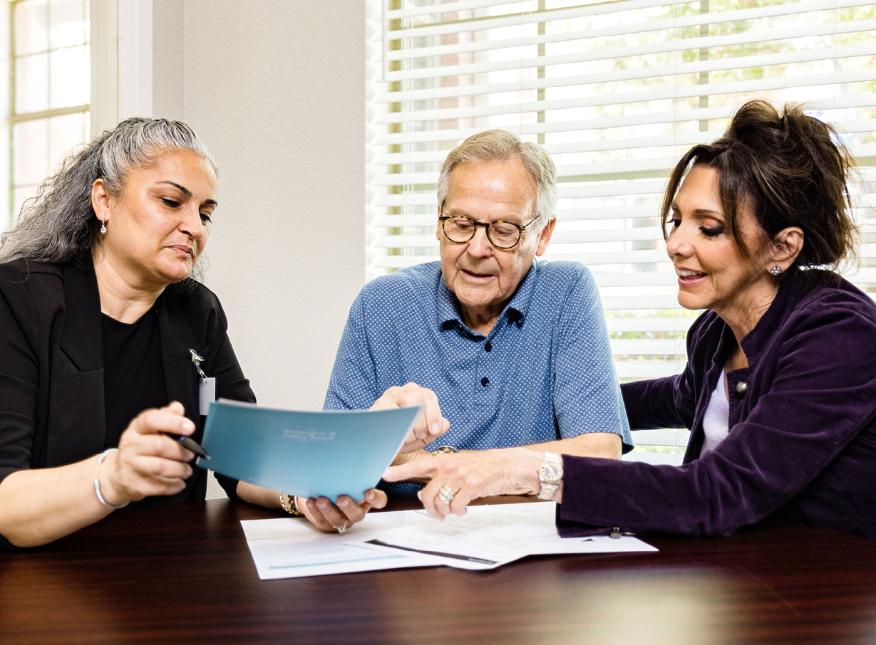 A senior man and two female caregivers help him find a senior living advisor