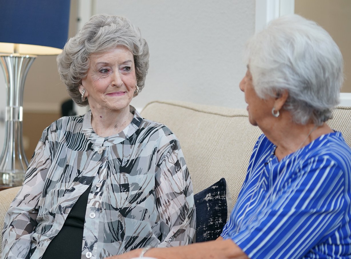 Two senior women sitting on a couch discussing setting a budget for senior living