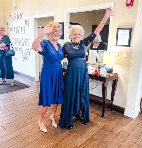 Two senior women dancing in dresses and celebrating a birthday together