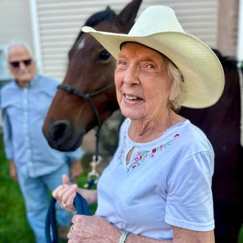 Woman wearing a cowboy hat leading a brown horse by the reins
