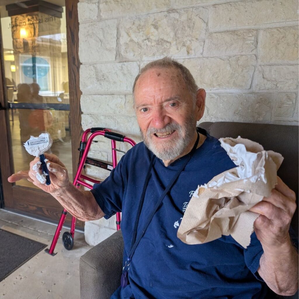 Man holds shaving cream and razor after playing the balloon beard game with fellow residents