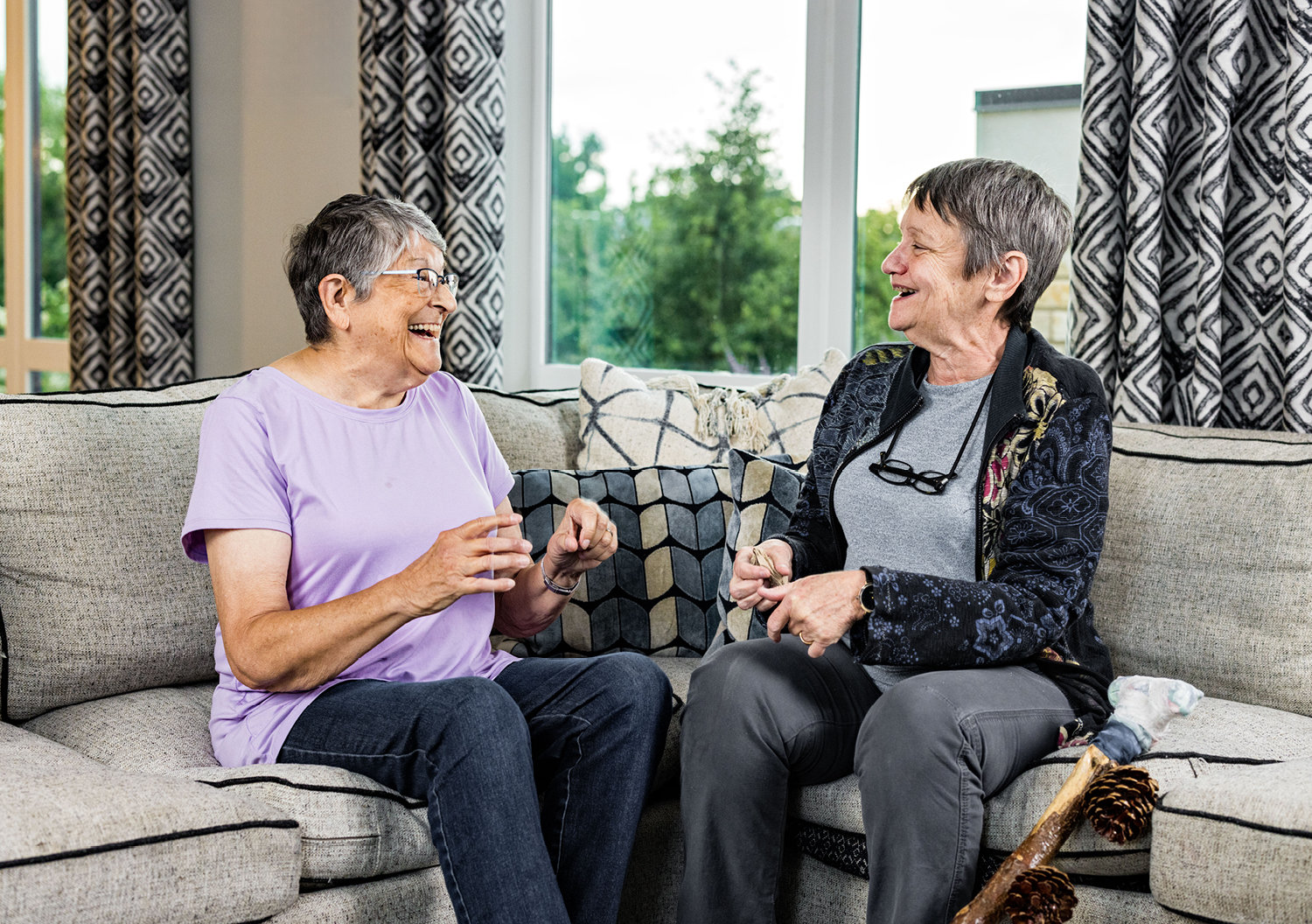 Two women laughing and talking on a couch