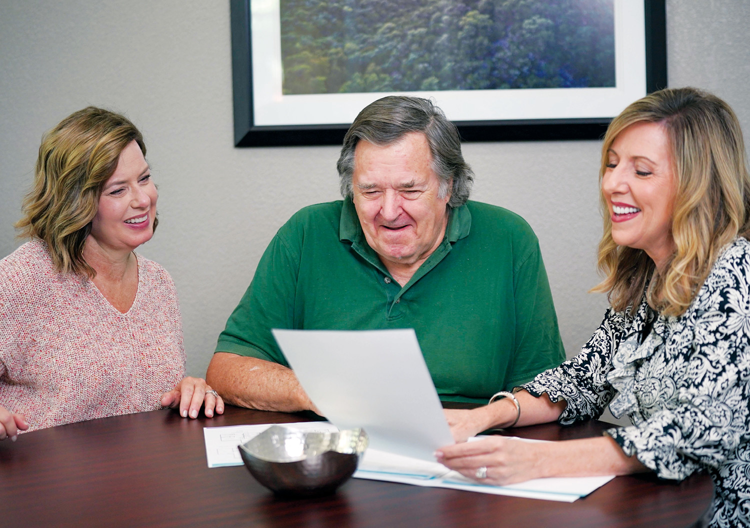 adult woman shows pricing at a senior living community to a daughter and her senior father