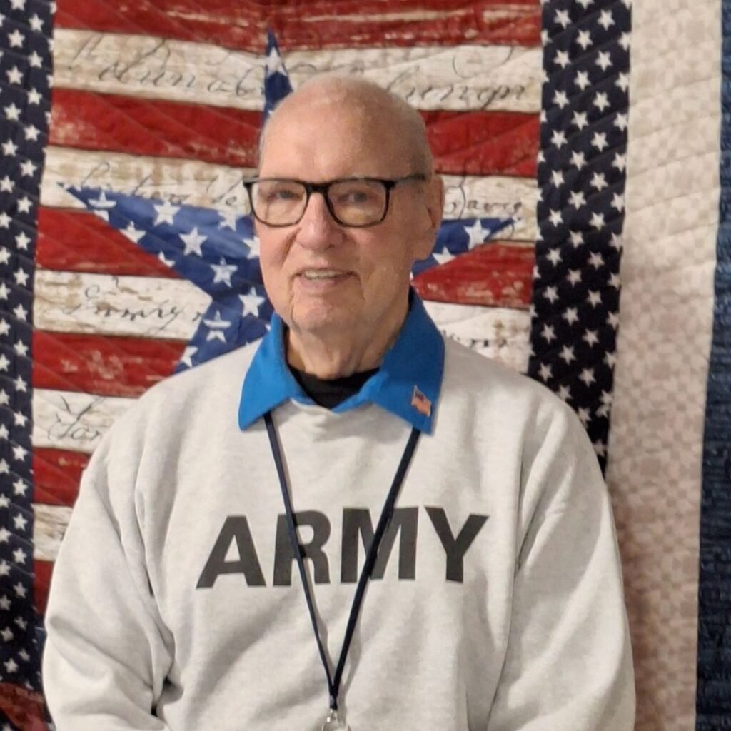 Veteran resident posing in front of red, white and blue freedom quilt