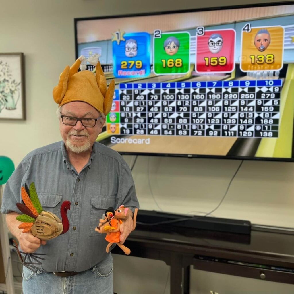 Resident is seen with trophy and turkey hat as Wii bowling champion at his community